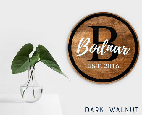 A personalized family name sign with dark walnut stain hanging on a white wall