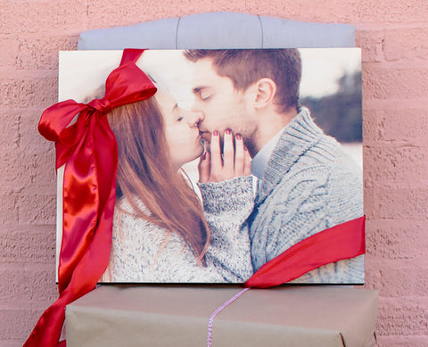 A photo of a couple kissing printing onto a photoboard wood print, in front of a brick wall.