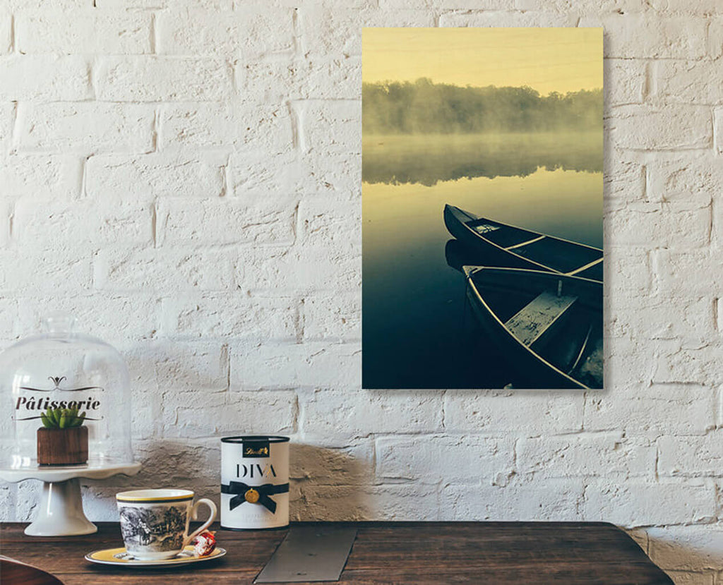 A readymade wood print on a white brick wall. Two canoes on a misty lake.