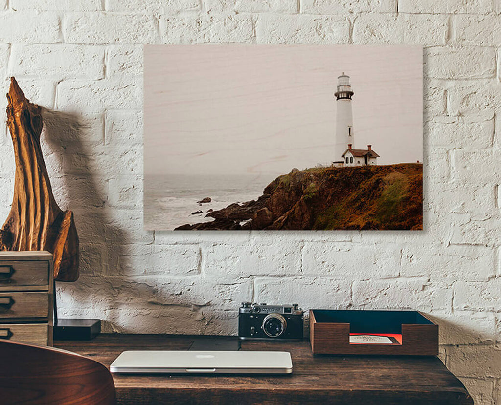 A readymade wood print on a white brick wall. A coastal lighthouse.