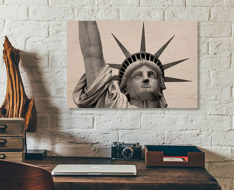 A readymade wood print on a white brick wall. A detailed view of the Statue of Liberty.