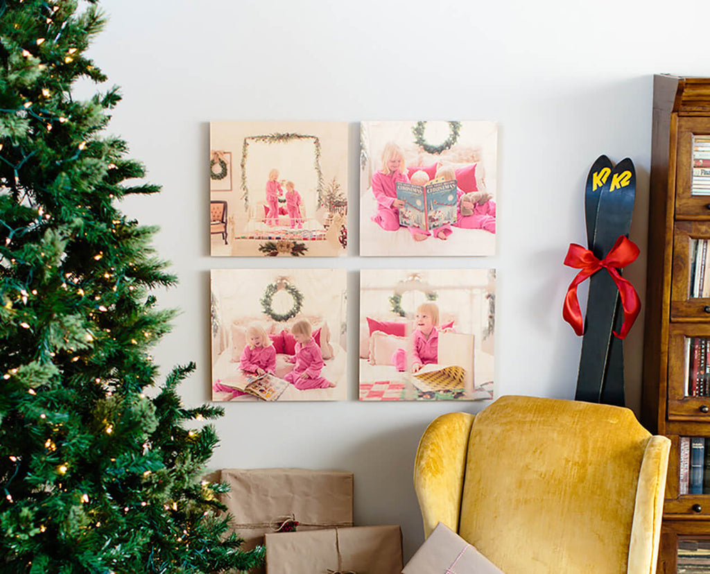 A set of 4 photoboard wood photo prints hanging in a grid pattern on a white wall next to a Christmas tree.